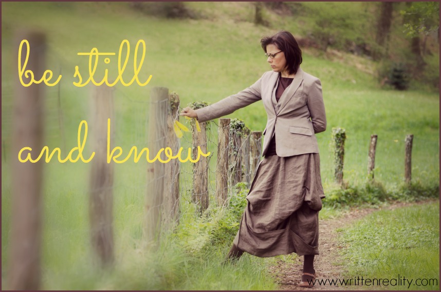 Elegant woman standing up on a forest road close to a fence and thinking